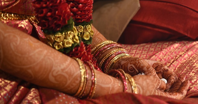 Traditionell bemalte Hände auf dem Schoss einer Inderin
