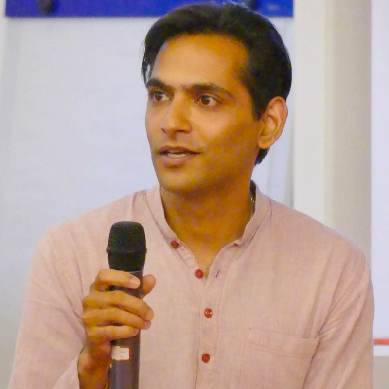 Dr. Devendra Prasad Mishra spricht mit einem Mikrofon bei einem Vortrag