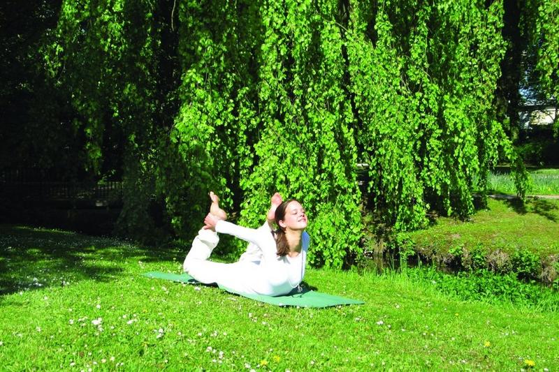 Frau macht Bogen Asana auf der Wiese