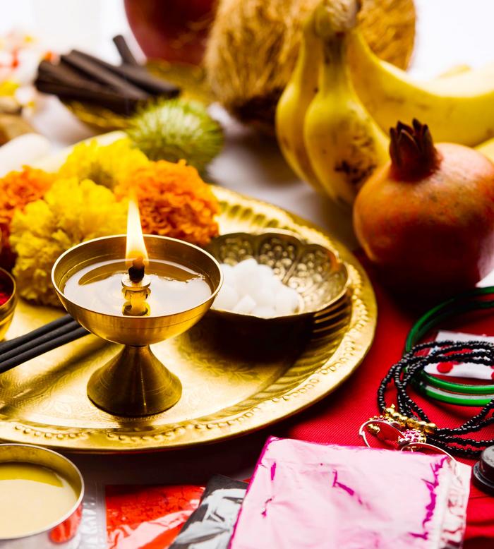 Brennende Öllampe auf goldenem Tablett mit Blüten, Schale und ayurvedischen Elementen