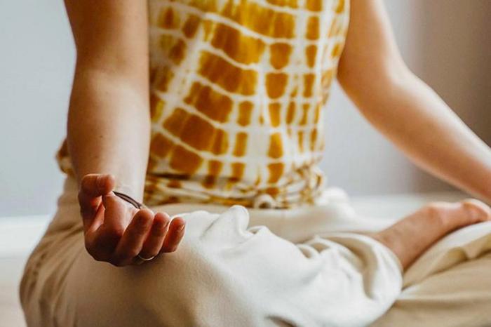 Nahaufnahme einer meditierenden Person im Sitzen mit Hand in Chin-Mudra