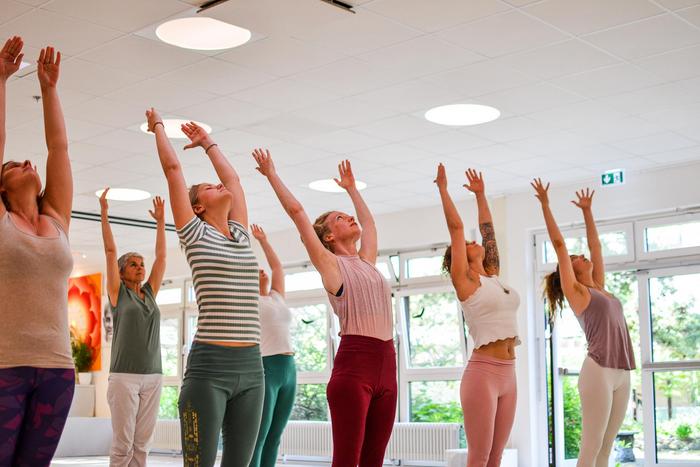 Frauen machen den Sonnengruß zusammen im Yogaraum