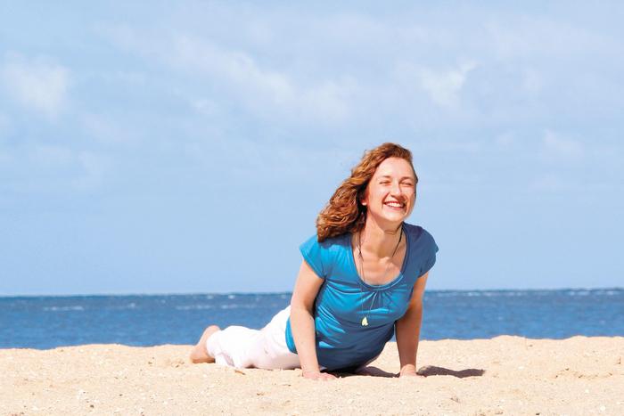 Frau am Strand in Kobra Yoga Pose