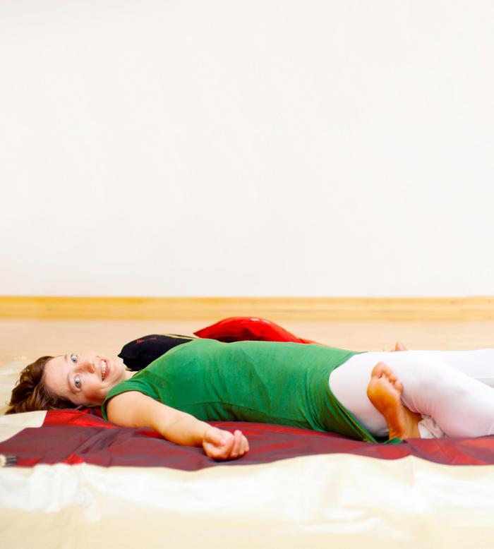 Frau in entspannter Liegehaltung bei der körperorientierten Yogatherapie