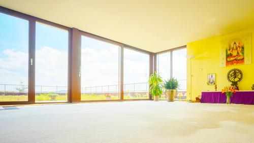 Lichtdurchfluteter Meditationsraum mit großer Fensterfront und Altar im Shivalaya