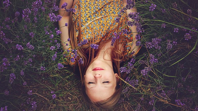 Frau liegt auf einer blauen Blumenwiese