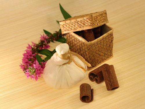 Gewürze in einem Bastkorb, ein ayurvedischer Kräuterstempel und Blüten
