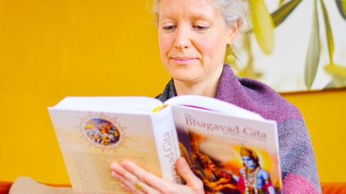 Frau liest aus der Bhagavad Gita