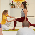 Im Yogaunterricht gibt die Yogalehrerin Hilfestellung 
