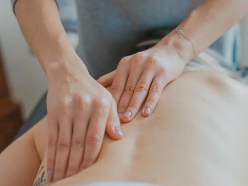 Ein Rücken wird von zwei Händen massiert nach der ayurvedischen Marmatherapie