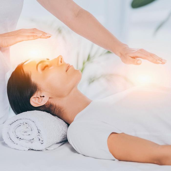 Zwei Hände werden achtsam über eine liegende Frau gehalten, als Anwendung energetischer Pranaheilung