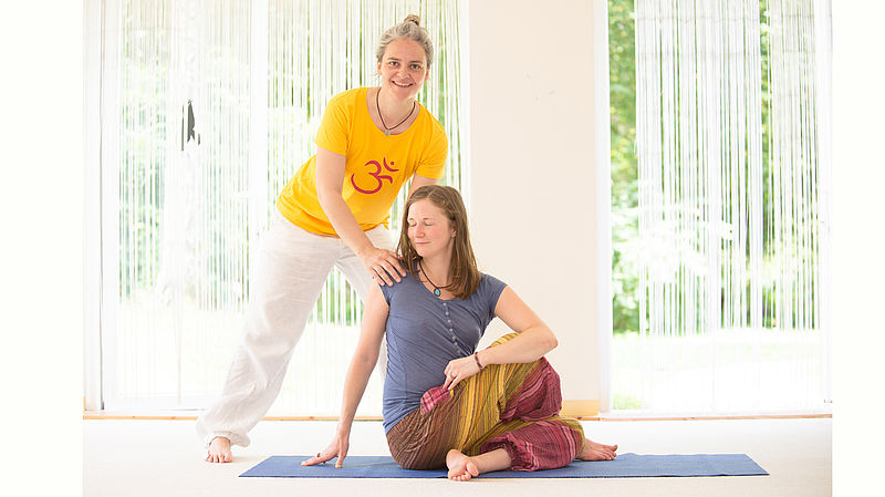 Yogalehrerin korrigiert Schülerin