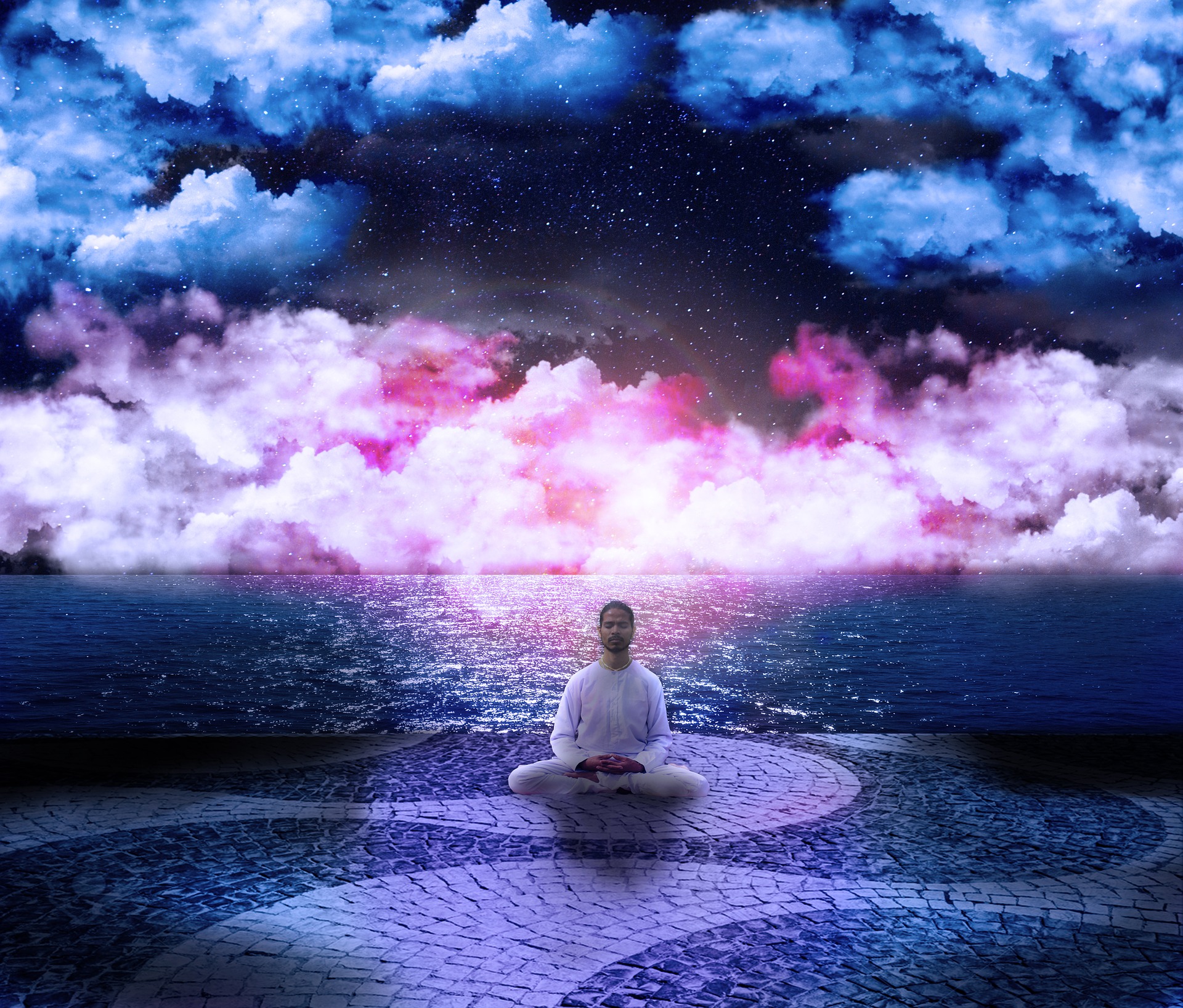 Ein Mann sitzt am Meer und meditiert, hinter ihm sind kosmisch gefärbte Wolken in blau, weiß und pink