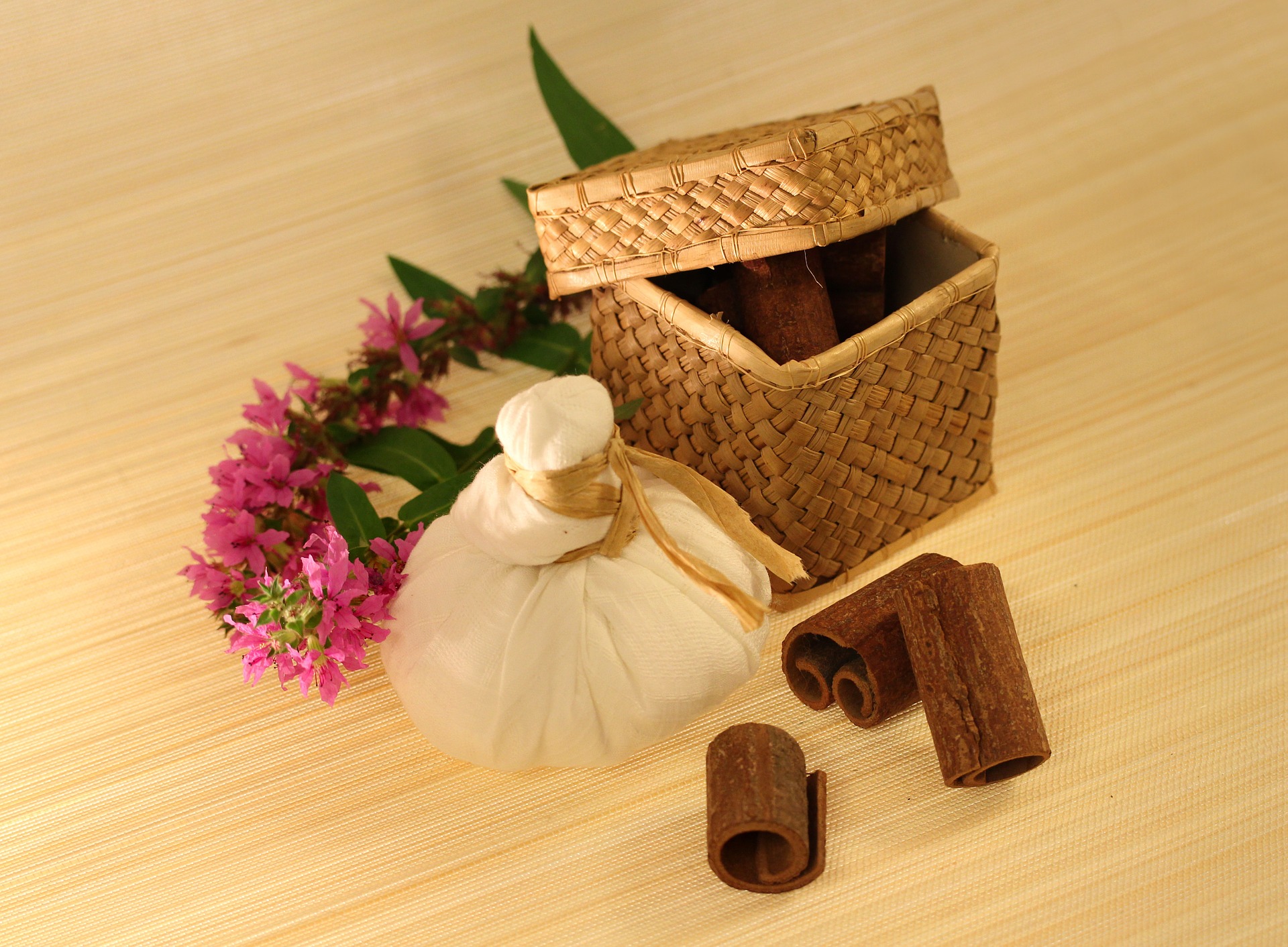 Gewürze in einem Bastkorb, ein ayurvedischer Kräuterstempel und Blüten